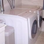 Laundry room with side-by-side front load washer and dryer, laundry sink, and trashcan