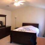 Bedroom with queen bed, dresser with mirror, and lamp