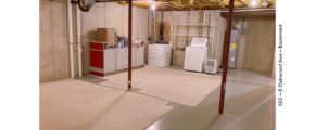 Unfinished basement with carpet squares, cabinets, and laundry machines