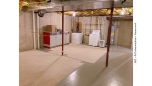 Unfinished basement with carpet squares, cabinets, and laundry machines