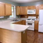 U-shaped kitchen with wood-tone cabinets, and white appliances