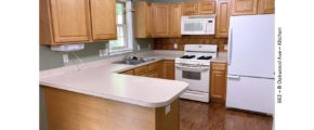 U-shaped kitchen with wood-tone cabinets, and white appliances