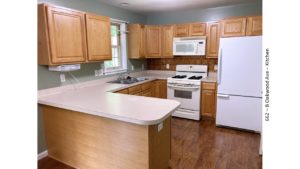 U-shaped kitchen with wood-tone cabinets, and white appliances