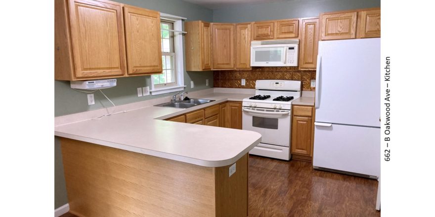 U-shaped kitchen with wood-tone cabinets, and white appliances