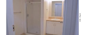 Bathroom with toilet, shower stall, vanity and mirror
