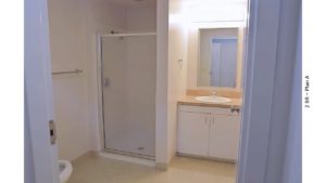 Bathroom with toilet, shower stall, vanity and mirror