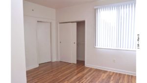 Unfurnished bedroom with wood-style floors, closet and large window