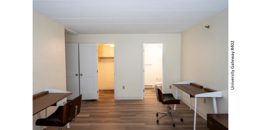 Bedroom with wood-style laminate flooring and 2 desks with chairs