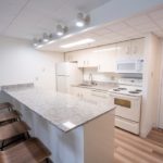 Kitchen with stone countertops, white metal cabinets, and white appliances