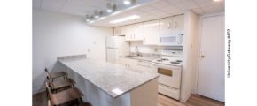 Kitchen with stone countertops, white metal cabinets, and white appliances