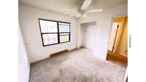 Carpeted bedroom with ceiling fan, closet, and large window