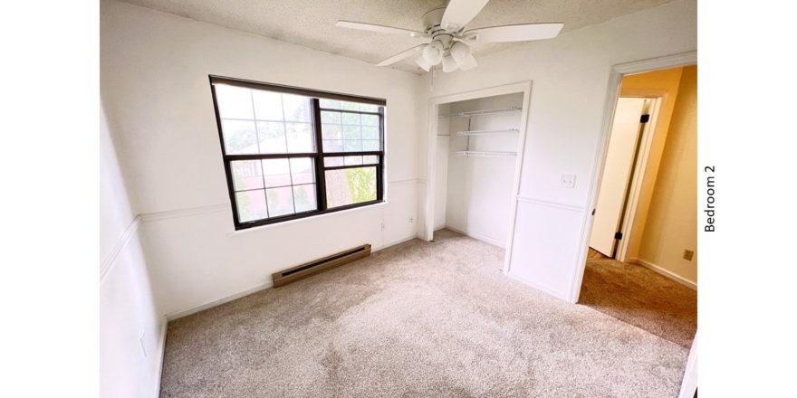Carpeted bedroom with ceiling fan, closet, and large window