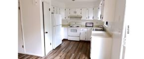 U-shaped kitchen with white cabinets, white appliances