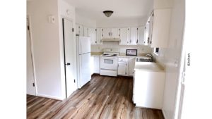 U-shaped kitchen with white cabinets, white appliances