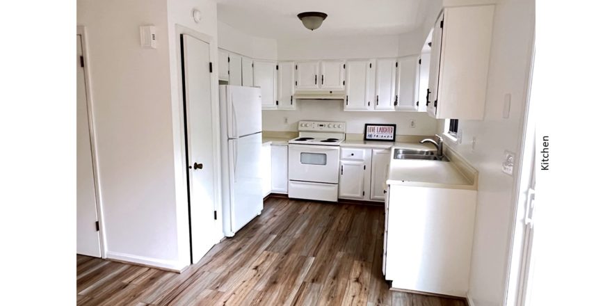 U-shaped kitchen with white cabinets, white appliances