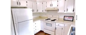U-shaped kitchen with white cabinets, white appliances