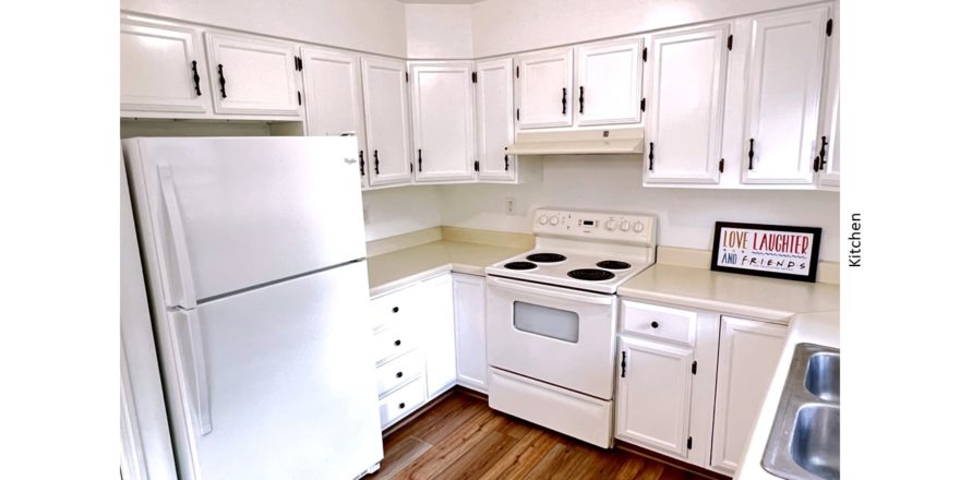 U-shaped kitchen with white cabinets, white appliances