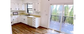 U-shaped kitchen with white cabinets, white appliances, and sliding door onto a deck