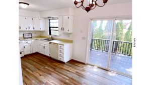 U-shaped kitchen with white cabinets, white appliances, and sliding door onto a deck