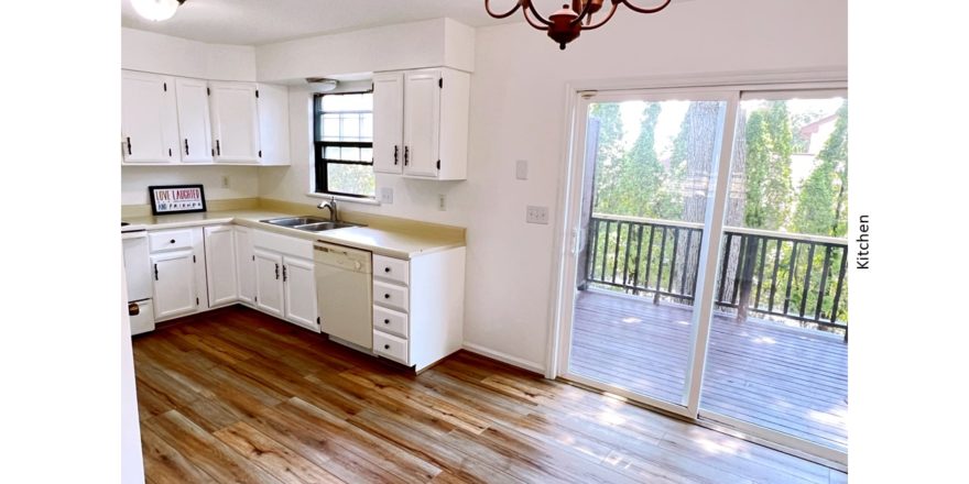 U-shaped kitchen with white cabinets, white appliances, and sliding door onto a deck