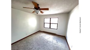 Carpeted bedroom with ceiling fan and large window