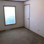 Unfurnished, carpeted bedroom with closet and a window