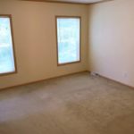 Unfurnished, carpeted bedroom with two windows