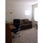 Bedroom set up as an office with a love seat, desk chair, and desk