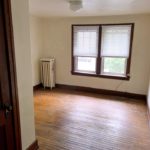 Unfurnished bedroom with hardwood floors, closet, and large windows