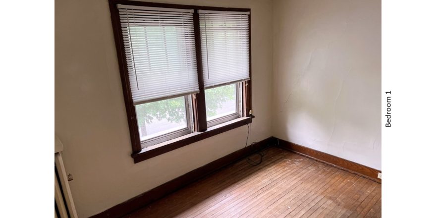 Unfurnished bedroom with hardwood floors and large windows