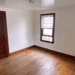 Unfurnished bedroom with hardwood floors, closet, and large window