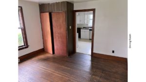 Unfurnished dining room with hardwood floors and large cupboard.