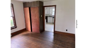 Unfurnished dining room with hardwood floors and large cupboard.