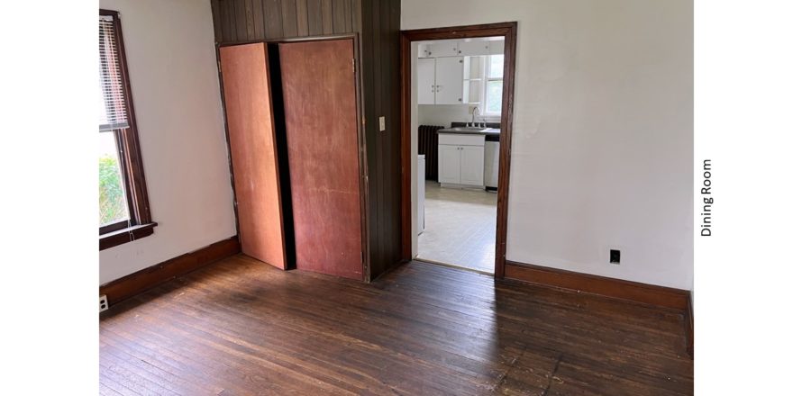 Unfurnished dining room with hardwood floors and large cupboard.