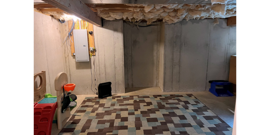 Unfinished basement with children's toys and large rug