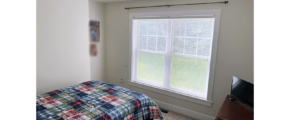 Bedroom with large window, bed, and dresser