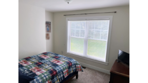 Bedroom with large window, bed, and dresser