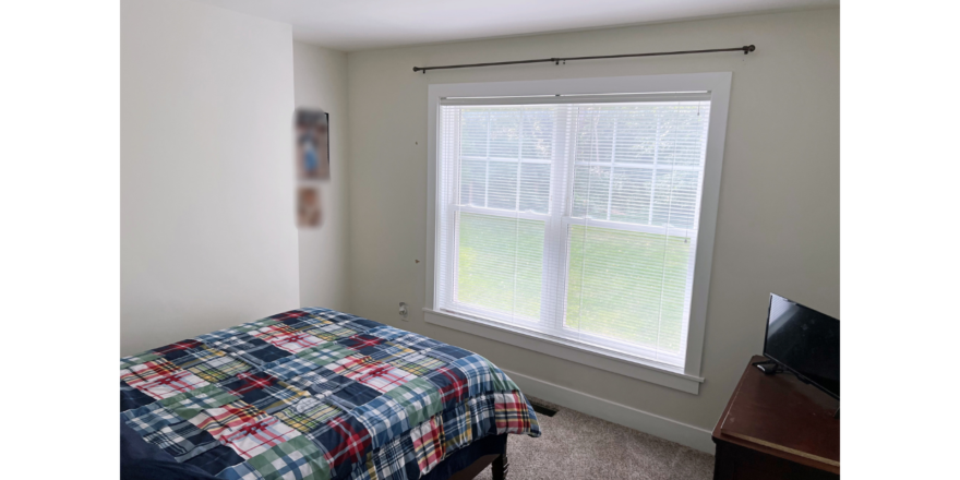 Bedroom with large window, bed, and dresser