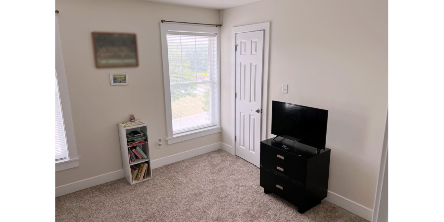 Bedroom with bookshelf, dresser, and TV