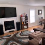 Living room with electric fireplace, large TV, sectional sofa, and dining table