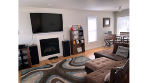 Living room with electric fireplace, large TV, sectional sofa, and dining table