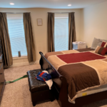 Owner's suite with large bed, ottoman, dresser and TV