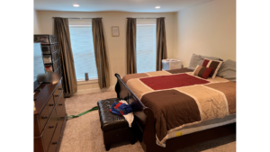 Owner's suite with large bed, ottoman, dresser and TV