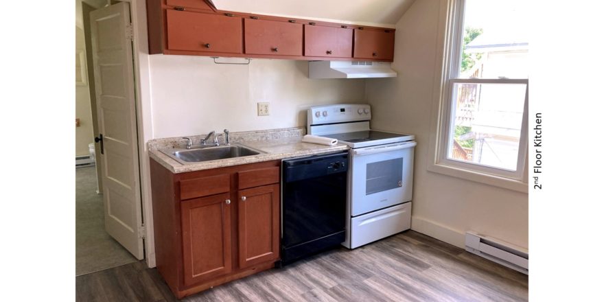 Kitchen with wood-tone cabinets, sink, black dishwasher, and white range oven