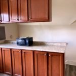 Kitchen counter with wood-tone cabinets and black microwave