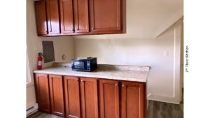 Kitchen counter with wood-tone cabinets and black microwave