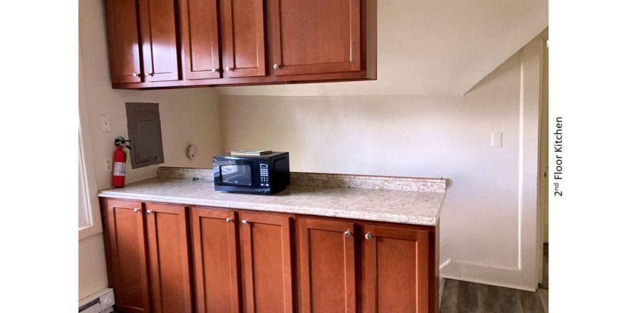 Kitchen counter with wood-tone cabinets and black microwave