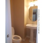 Half bathroom with pedestal sink, mirror, and toilet