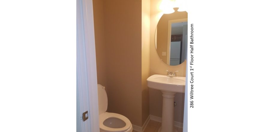 Half bathroom with pedestal sink, mirror, and toilet