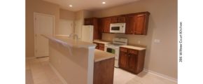 Galley kitchen with wood-tone cabinets, white appliances, and breakfast bar